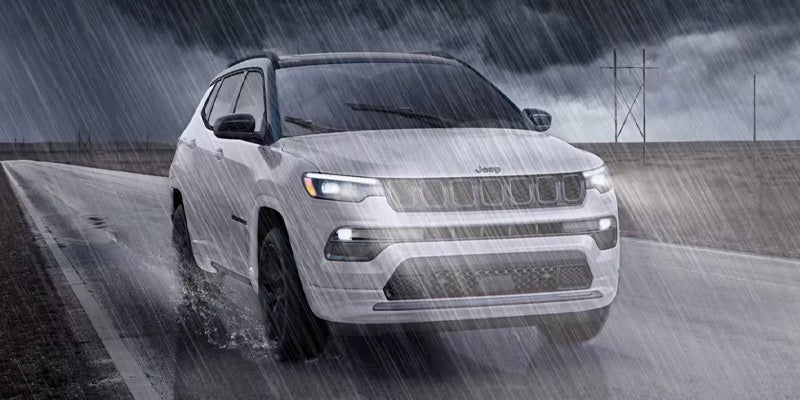 A photo of a 2025 Jeep Compass driving in the rain.