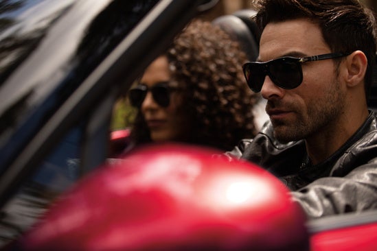 a close up shot of a couple sitting in a red convertible 