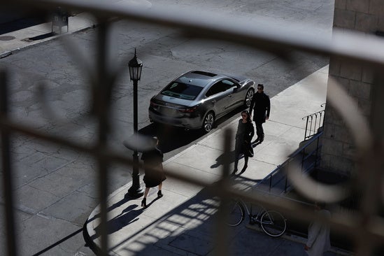 a three quarter overhead view of a street with a man and a woman in sunglasses walking 