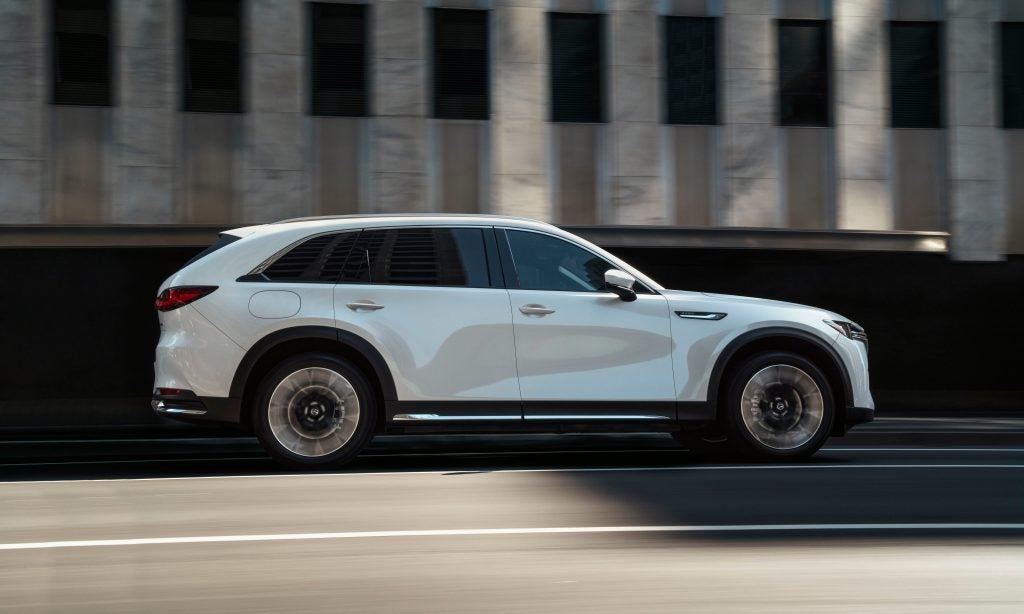 a white maza cx 90 driving on a road past granite stripes