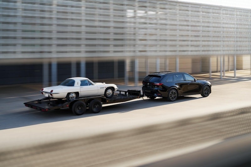 a black suv tows a white corvette