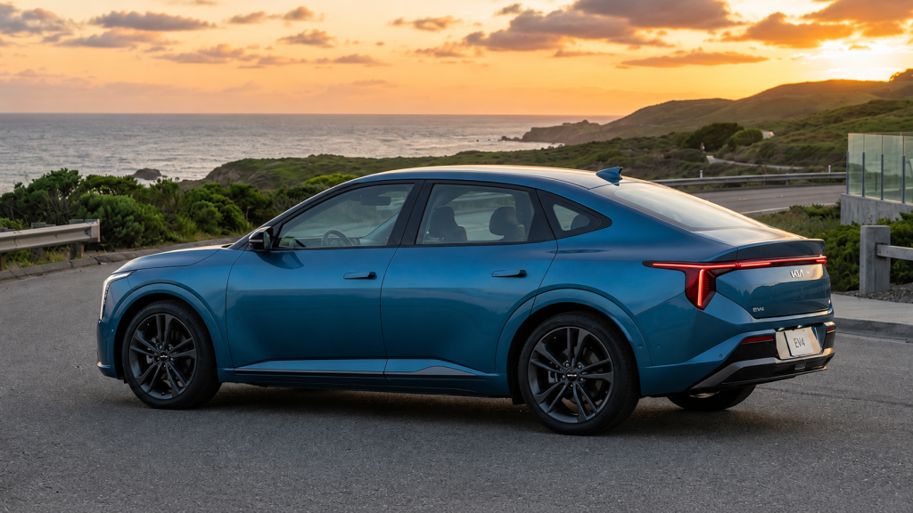 Blue Kia EV4 electric sedan parked beside a coastal road overlooking the ocean during sunset, showcasing its sleek modern design and aerodynamic profile.