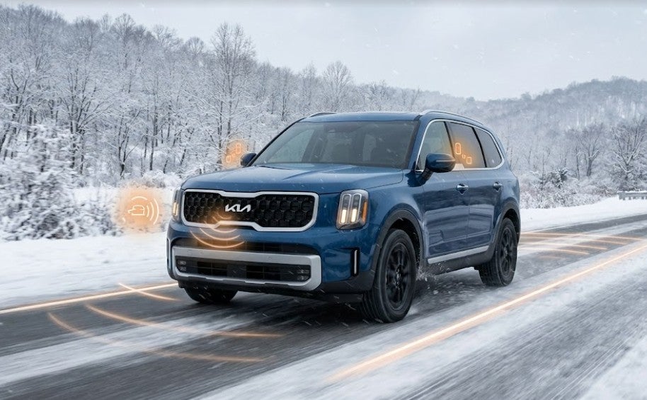 Blue Kia SUV driving on a snowy Ohio highway demonstrating Drive Wise active safety sensors and radar.