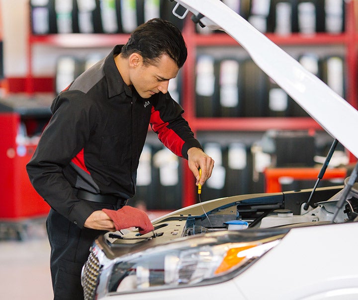 Man Checking Engine of Kia Vehicle.