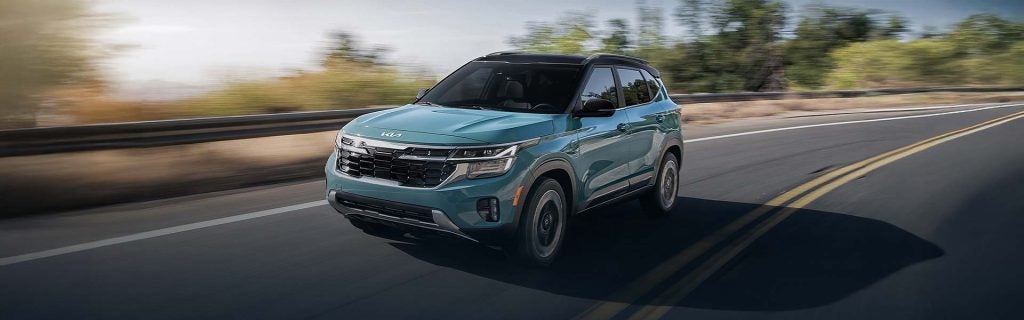 Kia Seltos compact SUV driving on an open highway with blurred scenery in the background, highlighting performance and modern design.