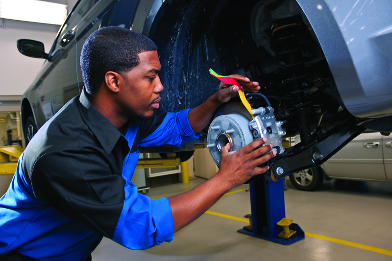 Automotive technician inspecting a vehicle brake system during professional brake service and repair