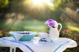 A table with blueberry custard and flowers on it outside.