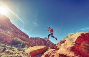 Man jumping across a rock on ahiking trail