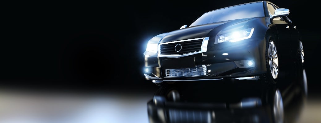 Front view of a logoless black sedan, modern looking, with its headlights on.