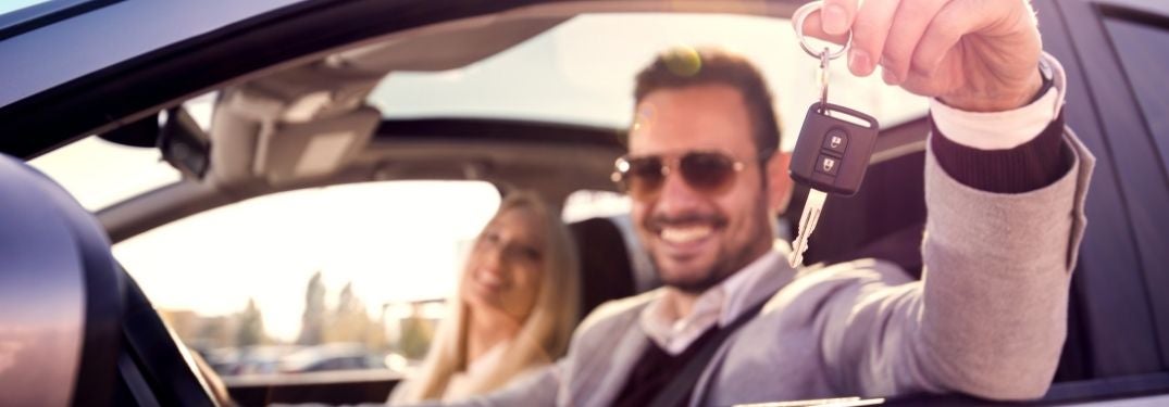 Young Couple in a New Car Holding a Key Up
