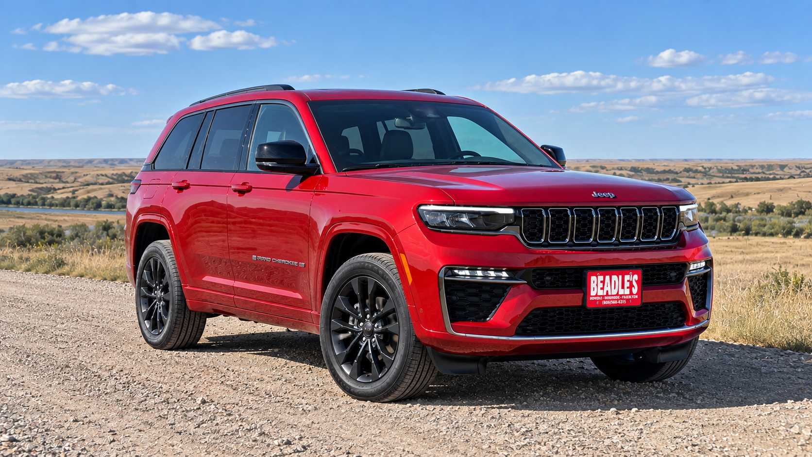 2027 Jeep Grand Cherokee in Red Hot on a South Dakota gravel drive, at Beadle's Chrysler Center