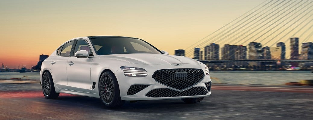 A white 2022 Genesis G70 parked in front of a cityscape