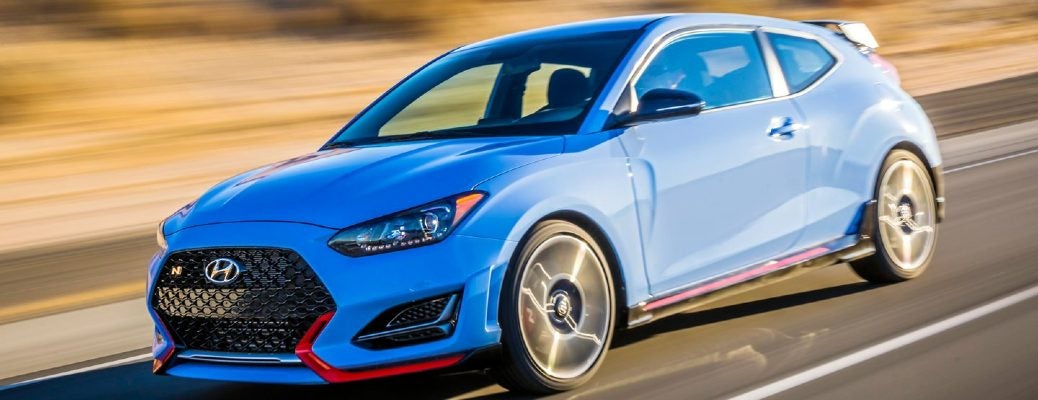 A light blue 2022 Hyundai Veloster driving on a race track, as seen from the side 3/4 driver's side
