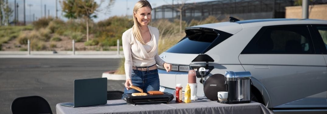 Woman Using Hyundai IONIQ 5 Vehicle to Load Charger at a Tailgate