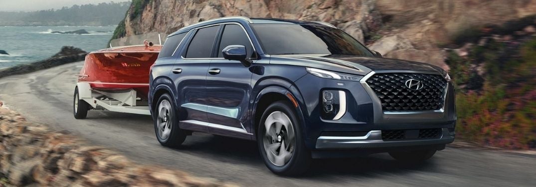 Blue 2022 Hyundai Palisade Towing a Boat on a Lake Road
