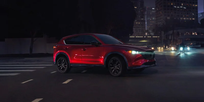 A 2025 Mazda CX-5 driving at night through a city street near Wooster, OH