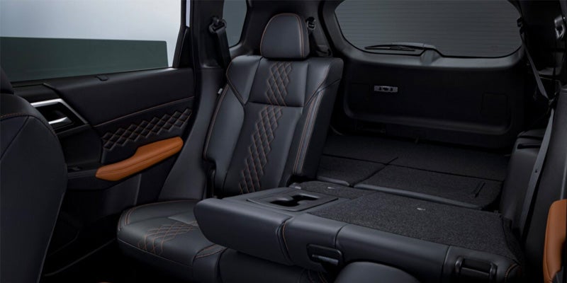 Car interior, dark gray leather seats with orange stitching, rear seats folded down and flat.