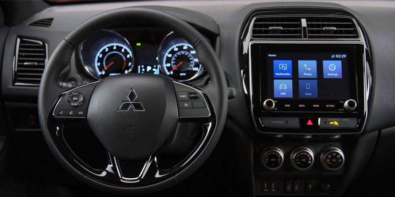 Interior view of a car dashboard showing a multifunction steering wheel, illuminated gauges, and a touchscreen display.