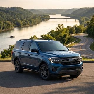 A wide-angle, cinematic automotive photograph of a sleek 2026 Ford Expedition in a deep metallic blue finish, parked on a scenic paved overlook high above the winding Ohio River. The setting features the characteristic rolling hills of the tri-state area with a mix of lush green trees and soft golden hour light reflecting off the water below. In the background, a distant bridge spans the river and a small fishing boat is visible on the water, emphasizing a lifestyle of adventure. The composition is a low-angle, three-quarter front view that highlights the vehicle’s imposing grille and modern LED headlights. The lighting is warm and natural, casting soft shadows across the winding asphalt road. The atmosphere is serene and capable, blending the ruggedness of a family weekend getaway with the polished look of a daily commuter, captured with a shallow depth of field and sharp, photorealistic detail.