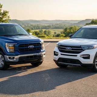 Cinematic commercial photography, wide-angle ground-level shot, a pristine 2025 Ford F-150 in iconic deep blue and a white 2025 Ford Explorer, parked prominently on a lot, set against the soft rolling hills and lush greenery of the Ohio River Valley, warm golden hour sunlight casting long soft shadows across the pavement, bright and inviting atmosphere, conveying transparency and community trust, hyper-realistic textures, vibrant natural colors, professional automotive lighting, high-gloss reflections on the vehicle bodies, shallow depth of field focusing on the front grills of the vehicles, crisp and clean aesthetic.