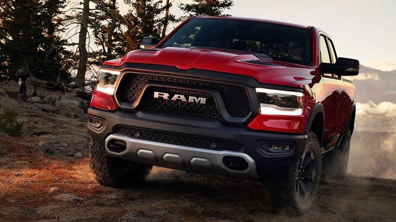 A red Ram pickup truck with the word "RAM" on its grill drives over dusty terrain.