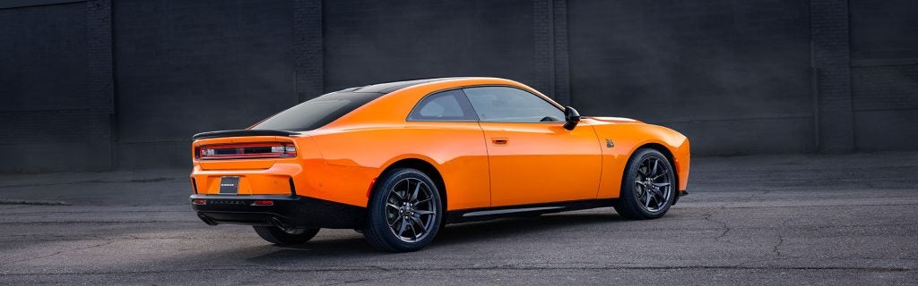 Orange Dodge Charger muscle car parked on pavement, showcasing its bold coupe design and performance-inspired styling.