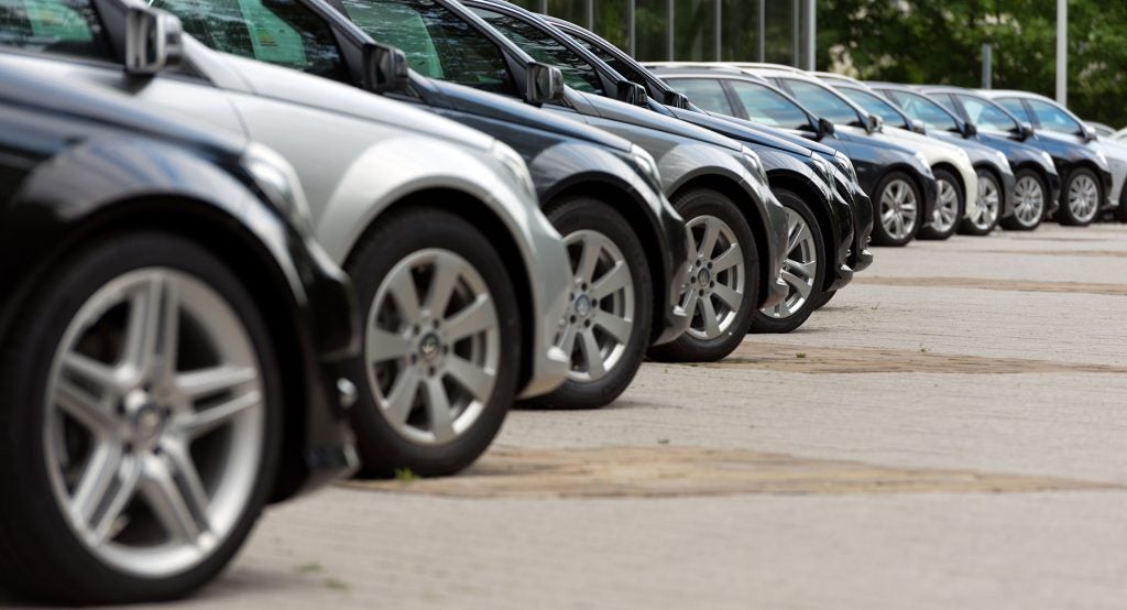 Row of parked used cars lined up in a dealership lot.