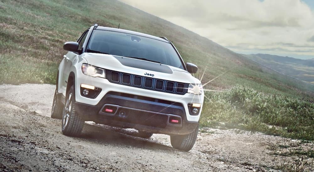 A white 2025 Jeep Compass Trailhawk is shown from the front.