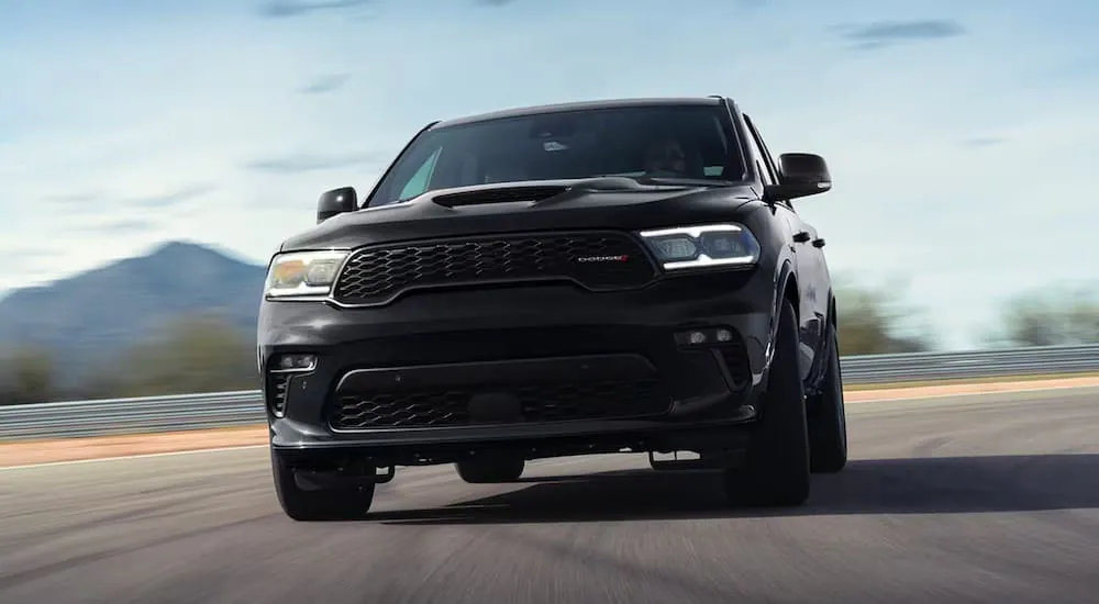 A black 2024 Dodge Durango driving on a highway to a Dodge dealer.