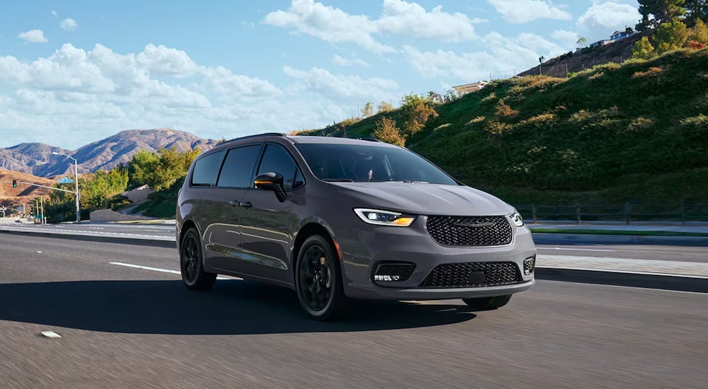 A grey 2024 Chrysler Pacifica Limited driving on an open highway.