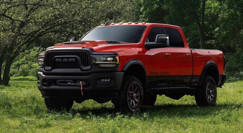 Red 2025 Ram 2500 parked off-road near a forest.