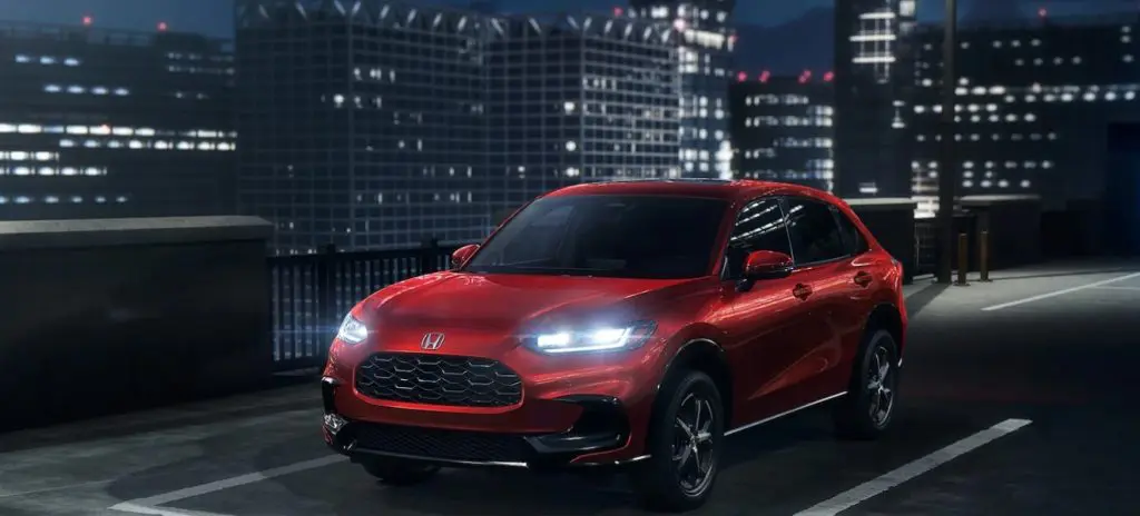 A red 2025 Honda HR-V drives at night with its highbeams on a city highway, showcasing the many safety features it has. Shop for yours at Stonecrest Honda!