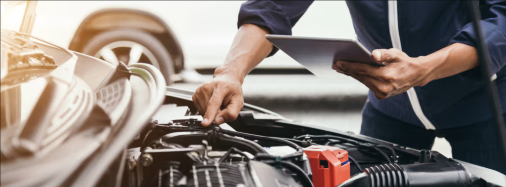 A mechanic's hand are working on the engine of a car with a hint of sunlight seen in the picture