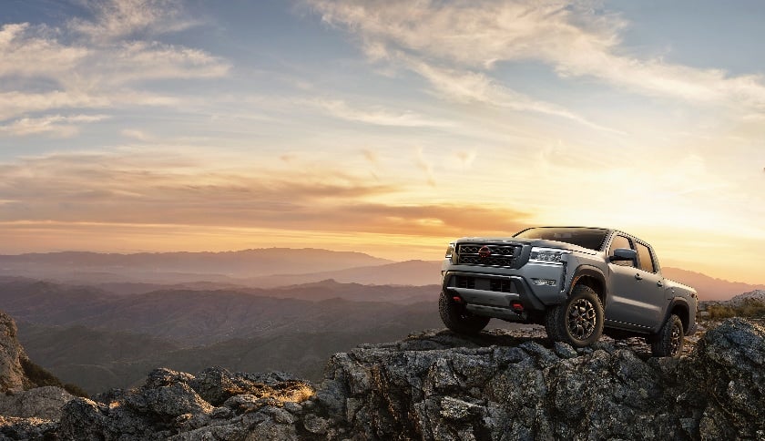 a truck parked on a rocky outcropping at sunset 