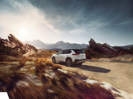 a white nissan rogue suv driving through the desert 