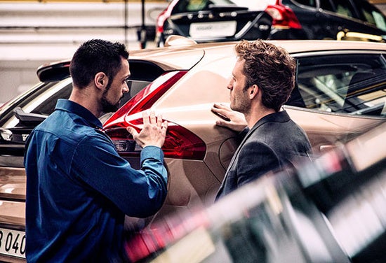two men touching the back of a beige suv 