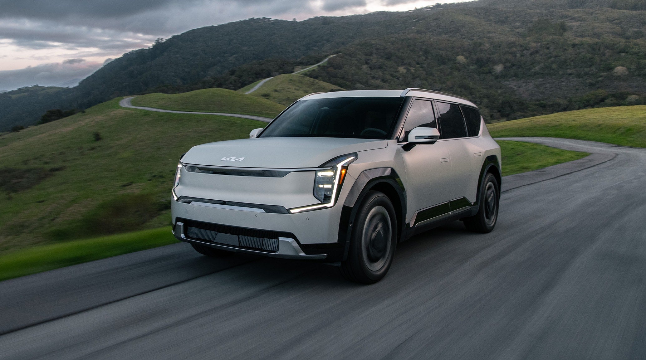 Silver 2024 Kia EV9 driving along a mountain road