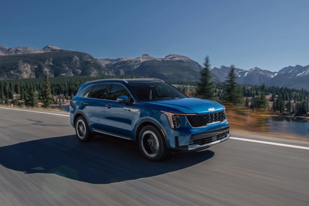 Blue 2025 Kia Sorento Hybrid driving along a mountainous road