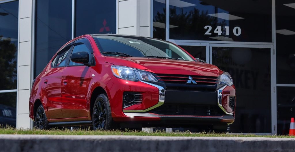 a red mitsubishi facing towards the camera parked on a hill
