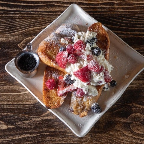 French toast with strawberries and blueberries on a white plate.