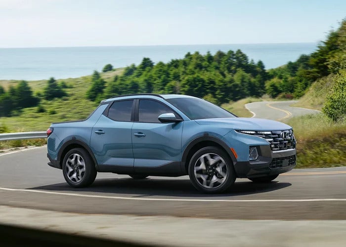 A Blue 2024 Hyundai Santa Cruz driving down the street