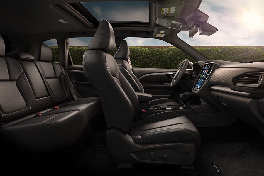 Interior view of a modern SUV featuring black leather seats, a sunroof, and a large touchscreen display.