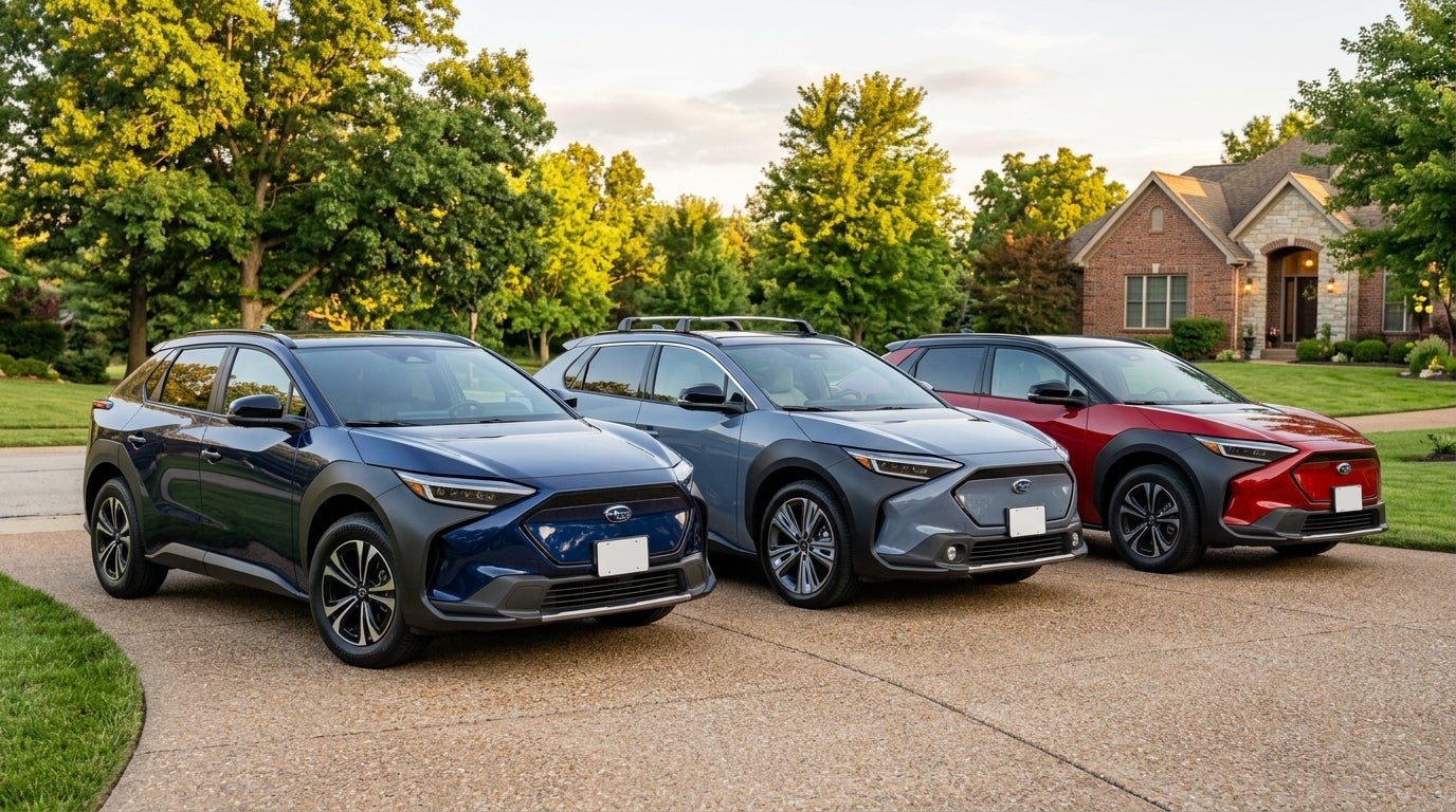Three Subaru Solterra electric SUVs in blue, grey, and red parked on a driveway in front of a brick home. (Representative image for illustration purposes only. Actual vehicle may vary based on trim and configuration.)