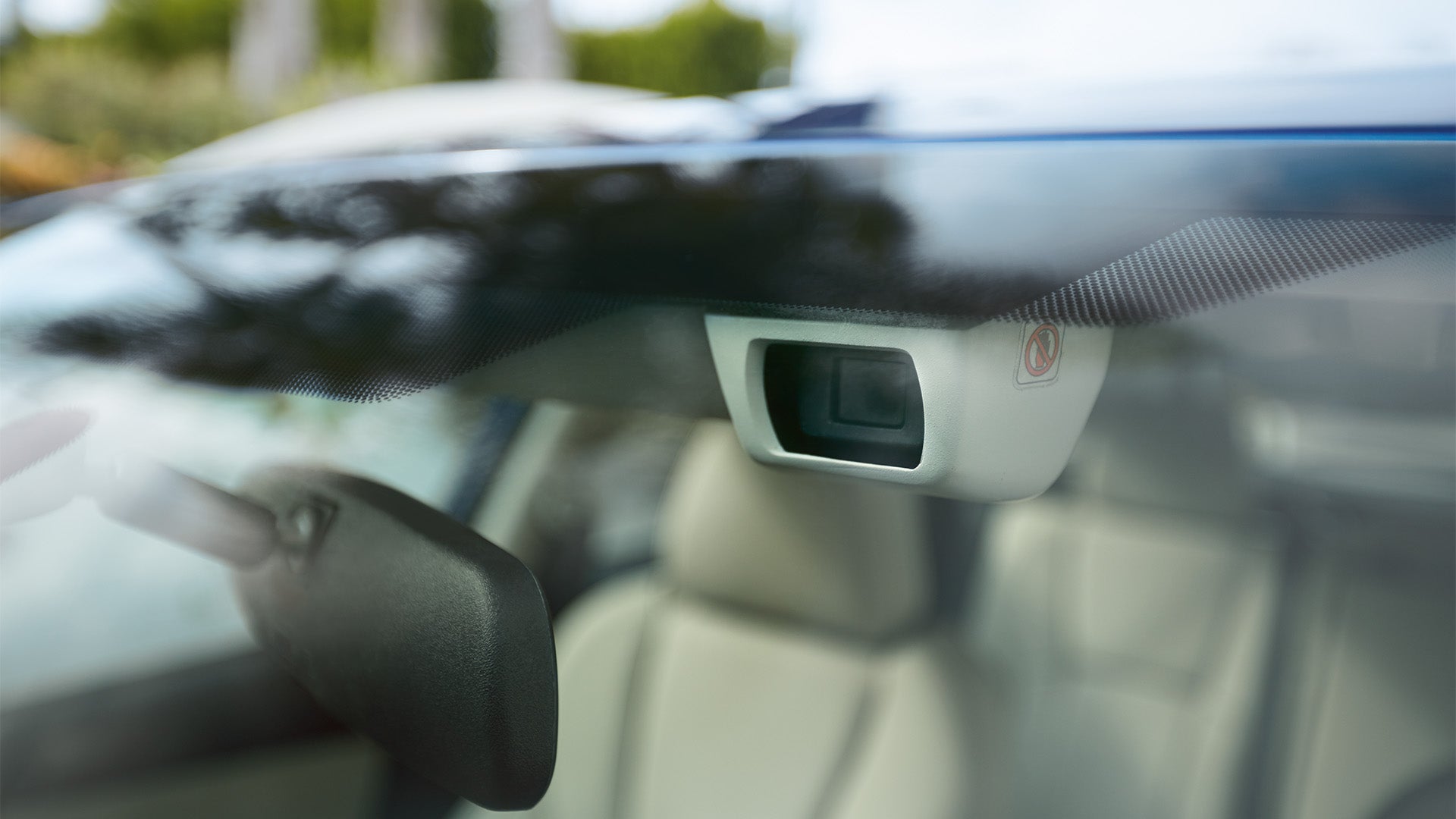 Close-up of a forward-facing safety camera mounted behind a car windshield.