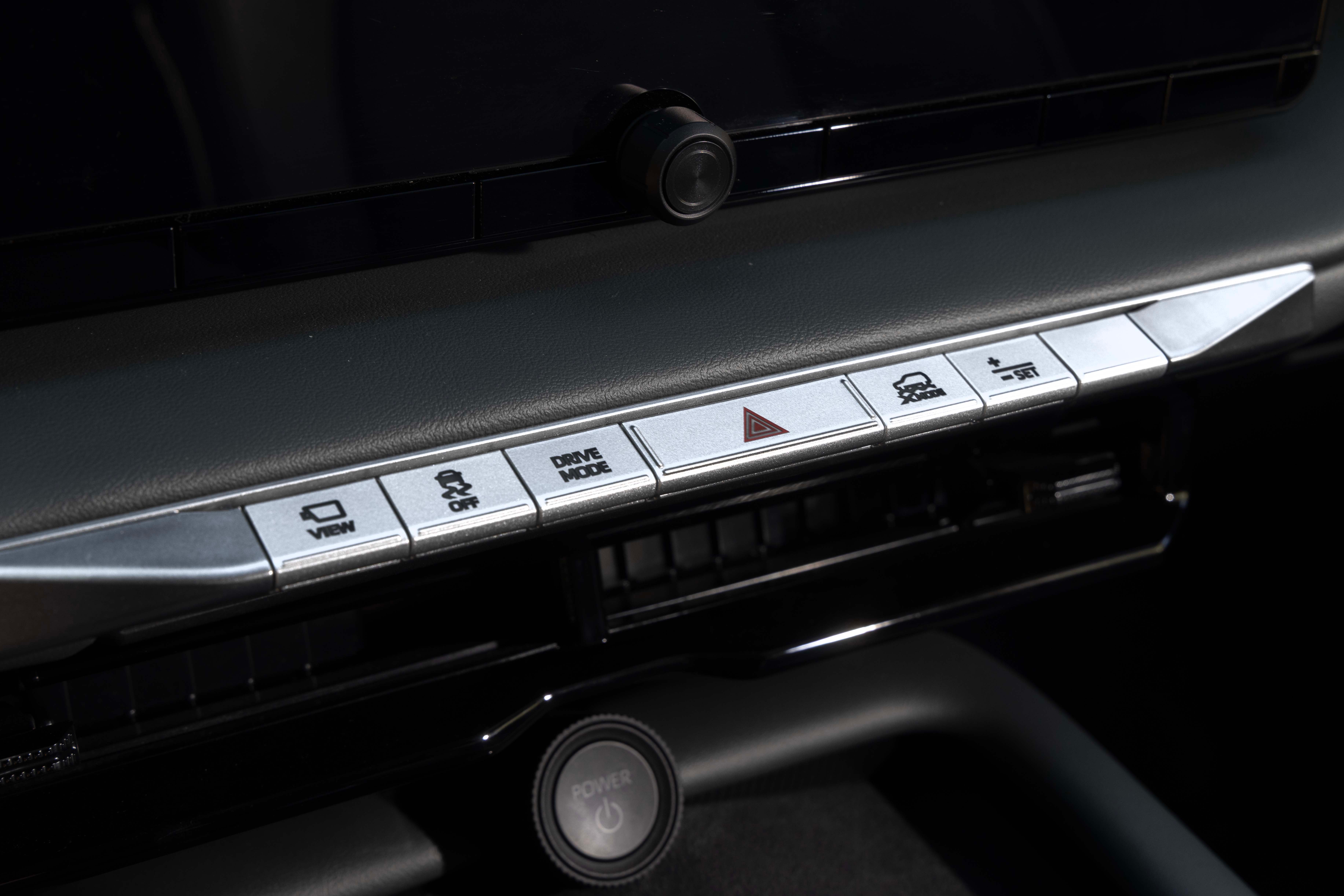 Car's center console buttons for drive modes, hazard lights, and screen view.