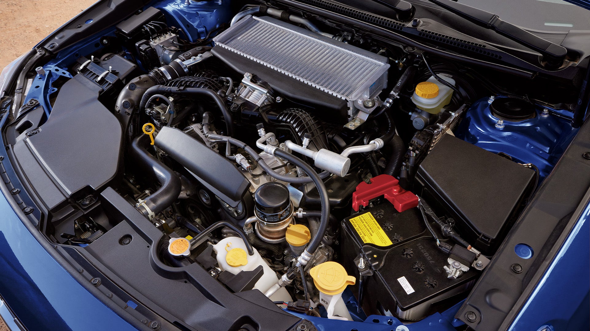 Close-up top view of a modern turbocharged car engine bay with blue exterior paint.