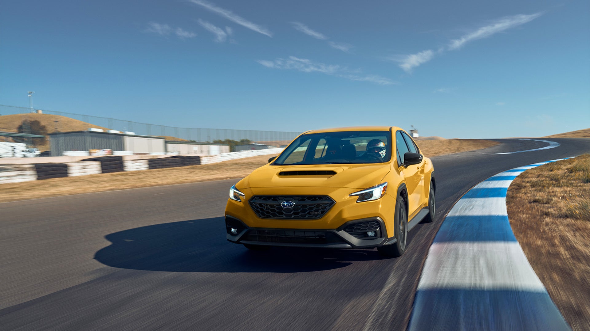 A high-performance Subaru WRX driving through a scenic road, showcasing its aggressive rally-inspired styling and aerodynamic profile.