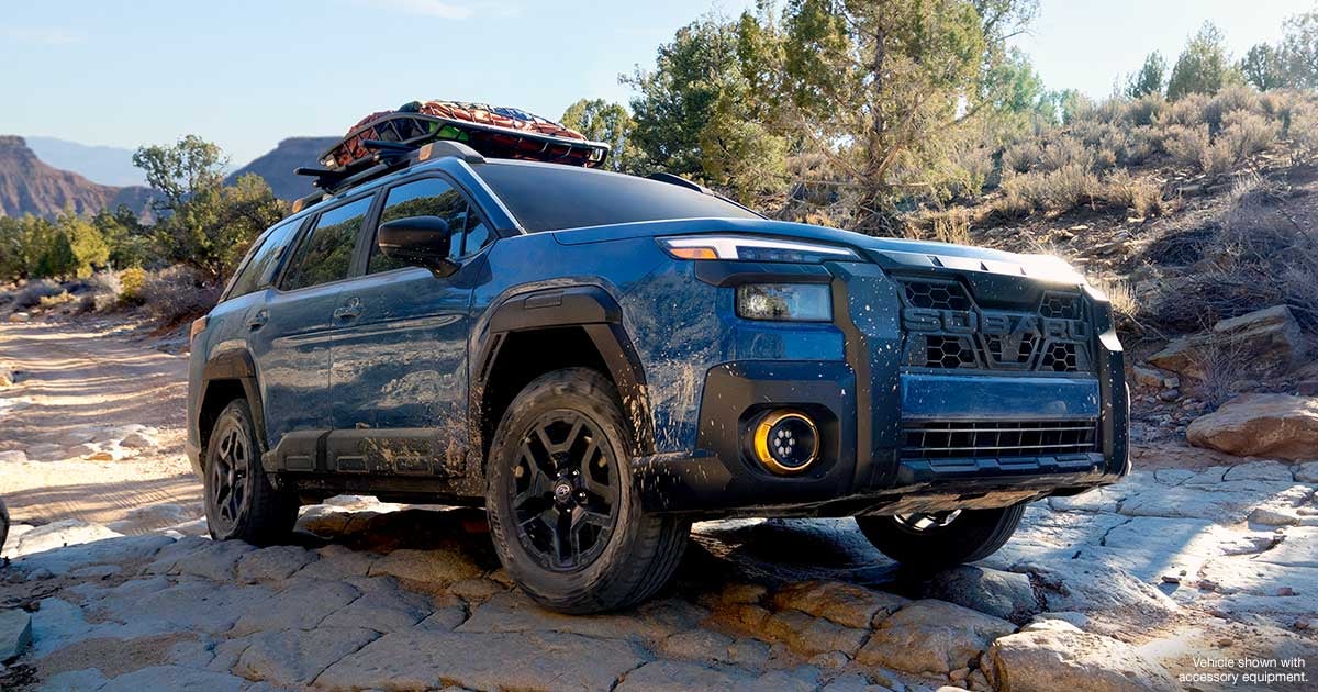 Blue Subaru Ascent Wilderness SUV navigating rocky terrain with accessories.