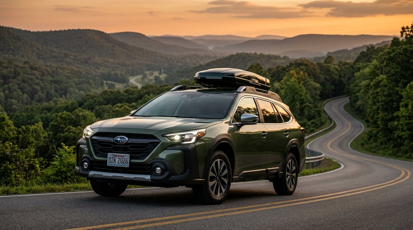 AI generated: Professional automotive commercial photography of a sleek 2026 Subaru Outback in a deep metallic forest green, positioned on a winding scenic road through the lush rolling hills of the Ozarks during golden hour, low-angle three-quarter front perspective, showcasing the redesigned aggressive front fascia with futuristic slim LED signature headlights and a bold rugged grille, high ground clearance, aerodynamic body lines reflecting the warm orange glow of the sunset, pristine metallic paint finish, sophisticated and adventurous mood, hyper-realistic textures, sharp focus on the vehicle with a soft bokeh background of misty hills and deciduous trees, clean cinematic lighting, high dynamic range, 8k resolution.