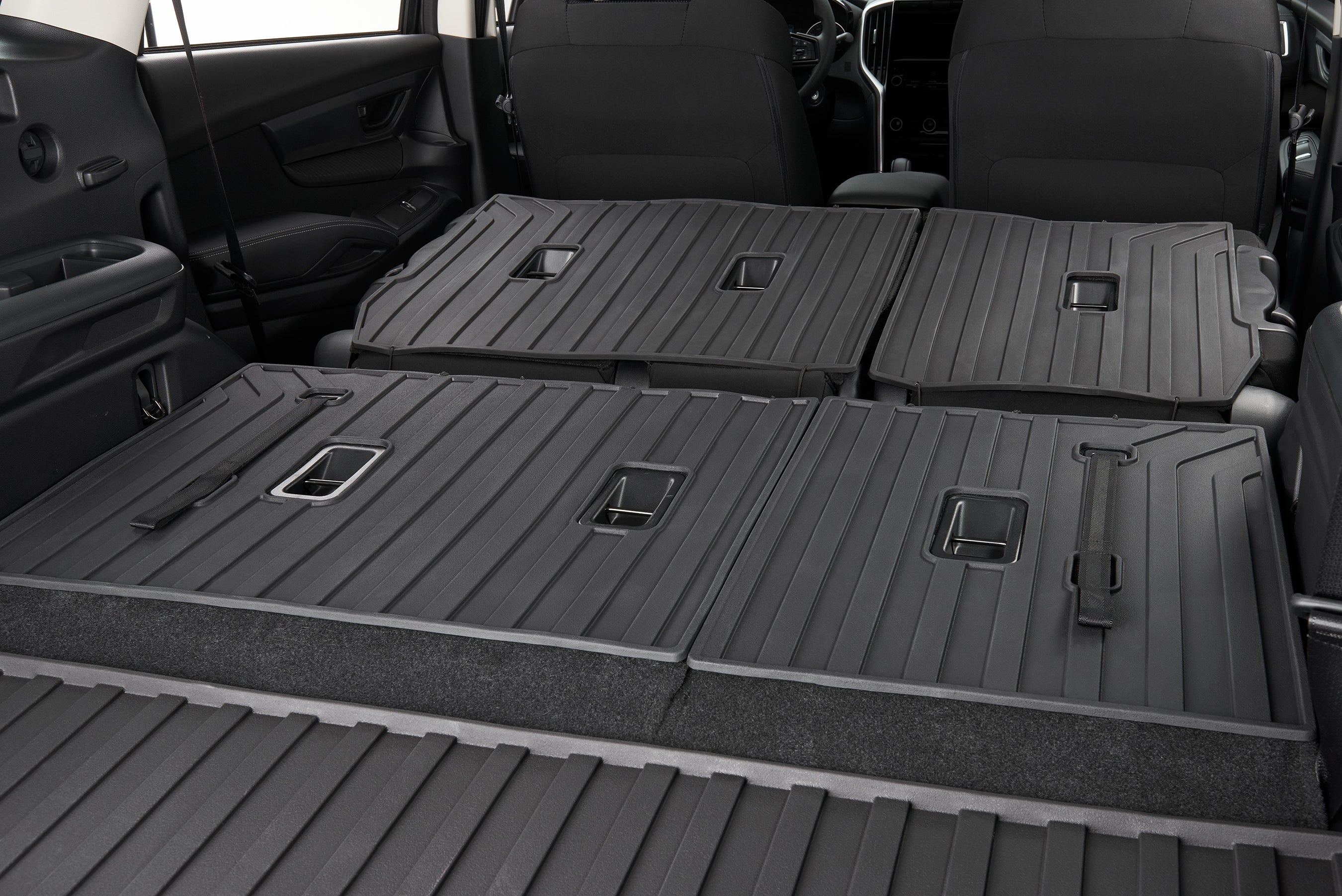 Black all-weather floor mats covering the folded rear seats and cargo area of a modern SUV.